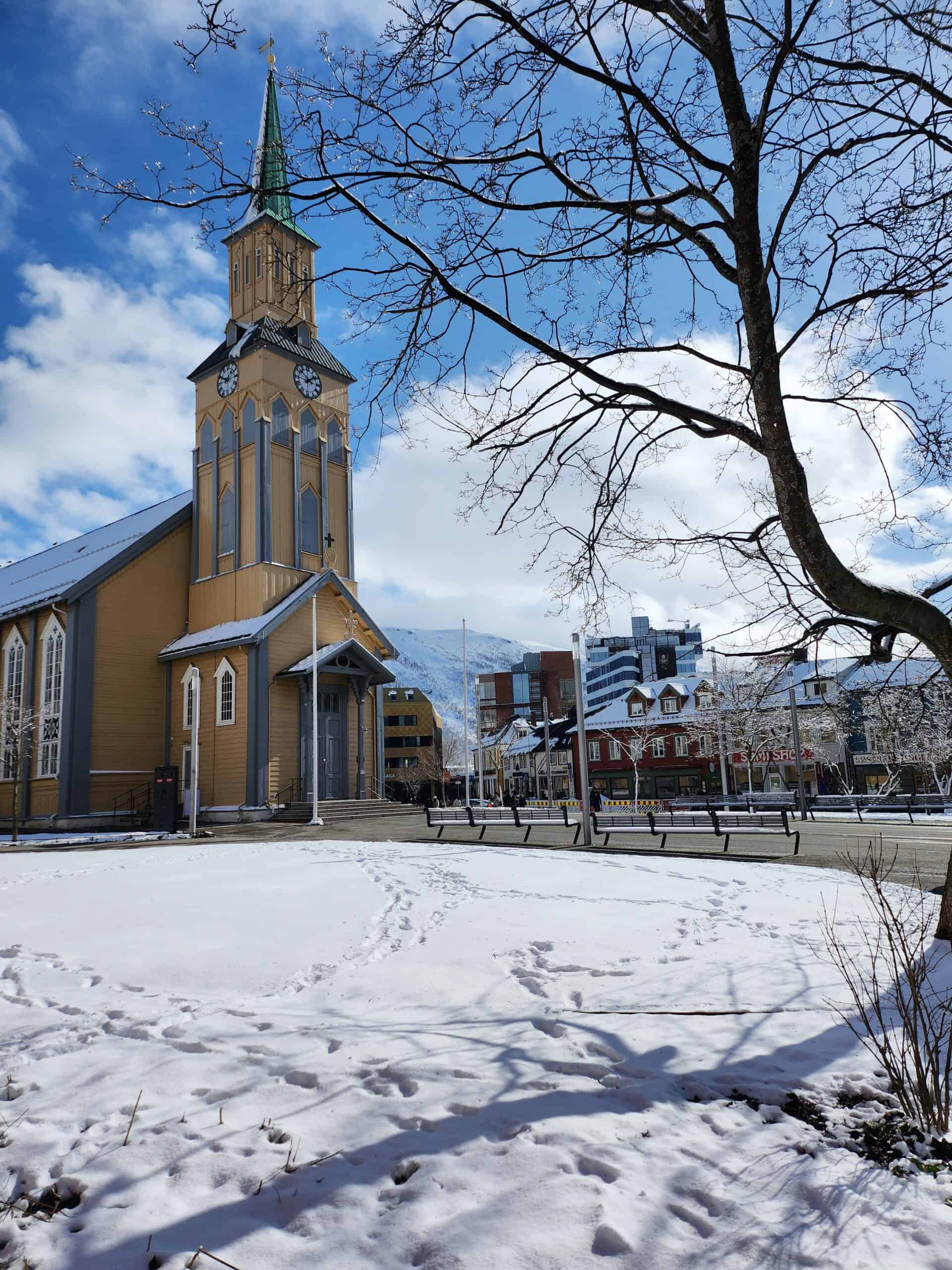 Tromsø church with snow-covered ground and blue sky in winter.