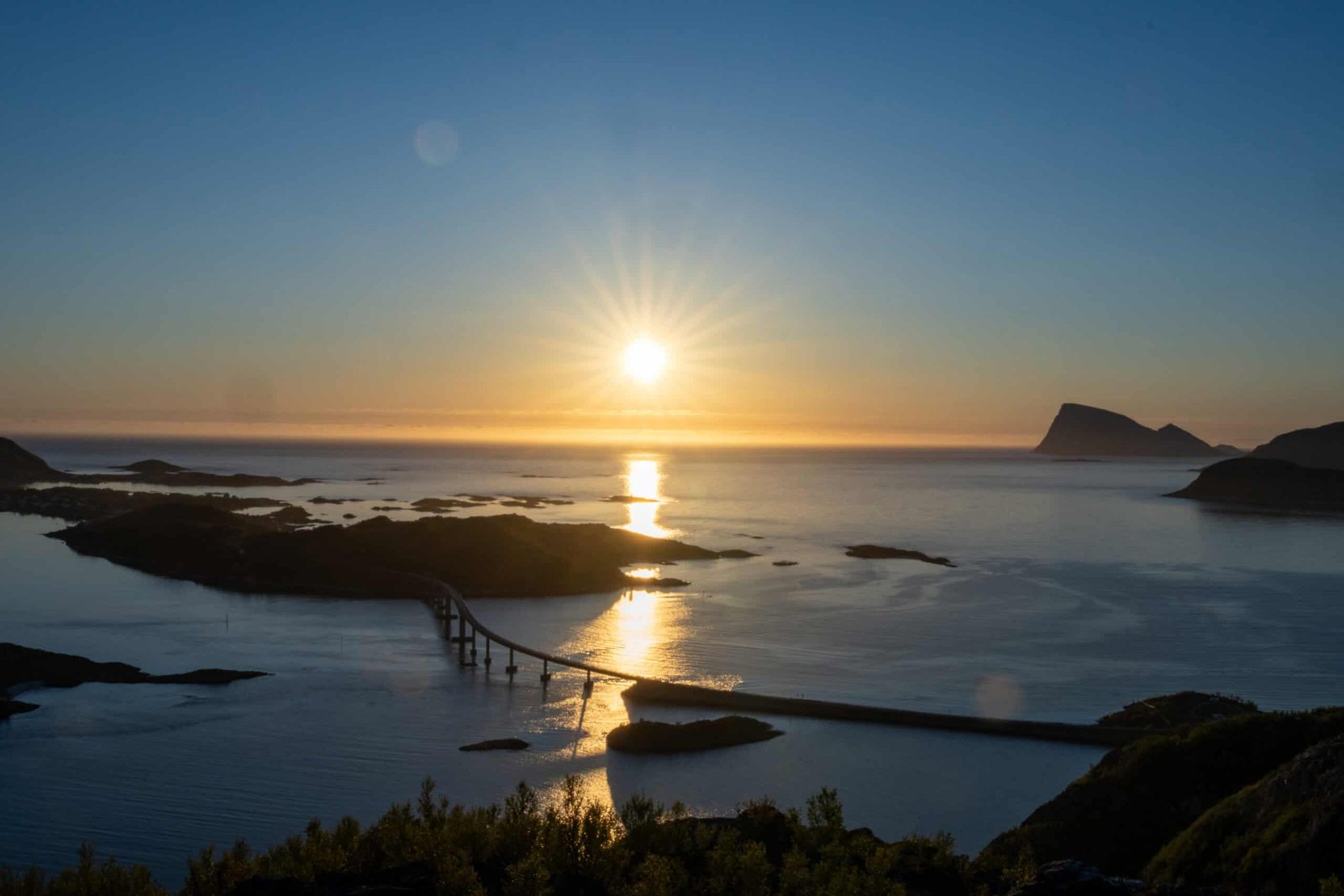 Beautiful sunset over Tromsø coast with calm waters and rocky islands.