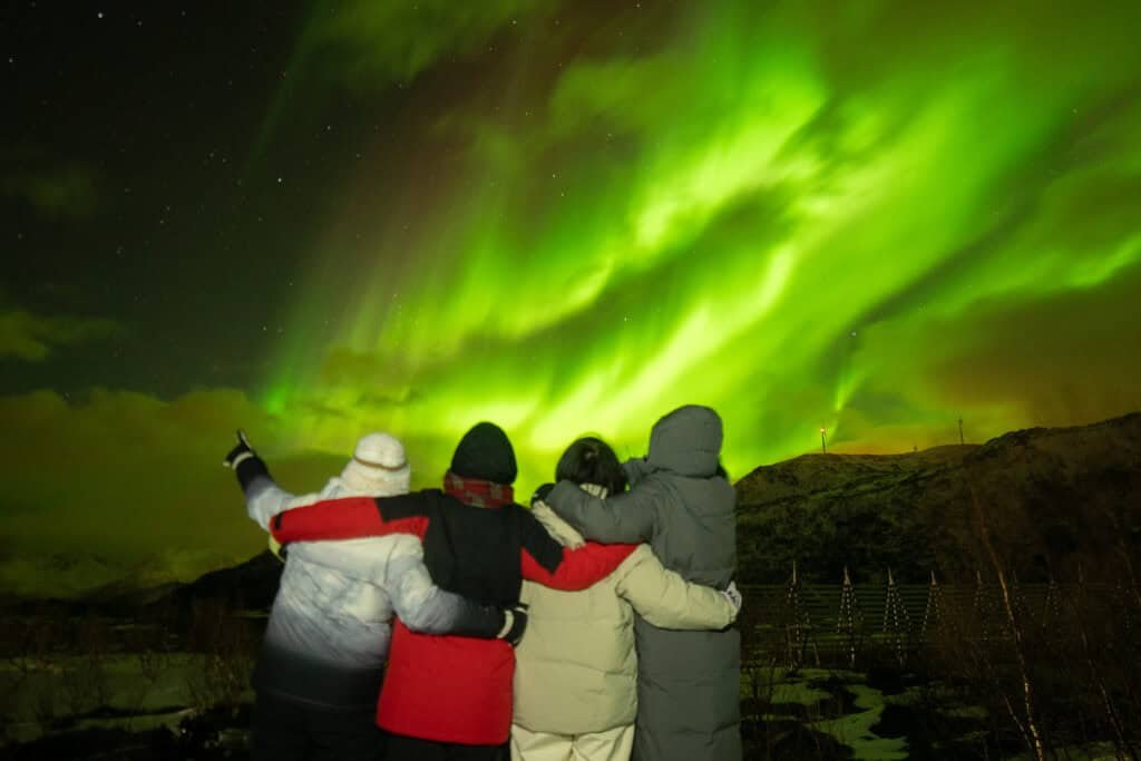 People watching the Northern Lights in Tromsø, Norway at night.
