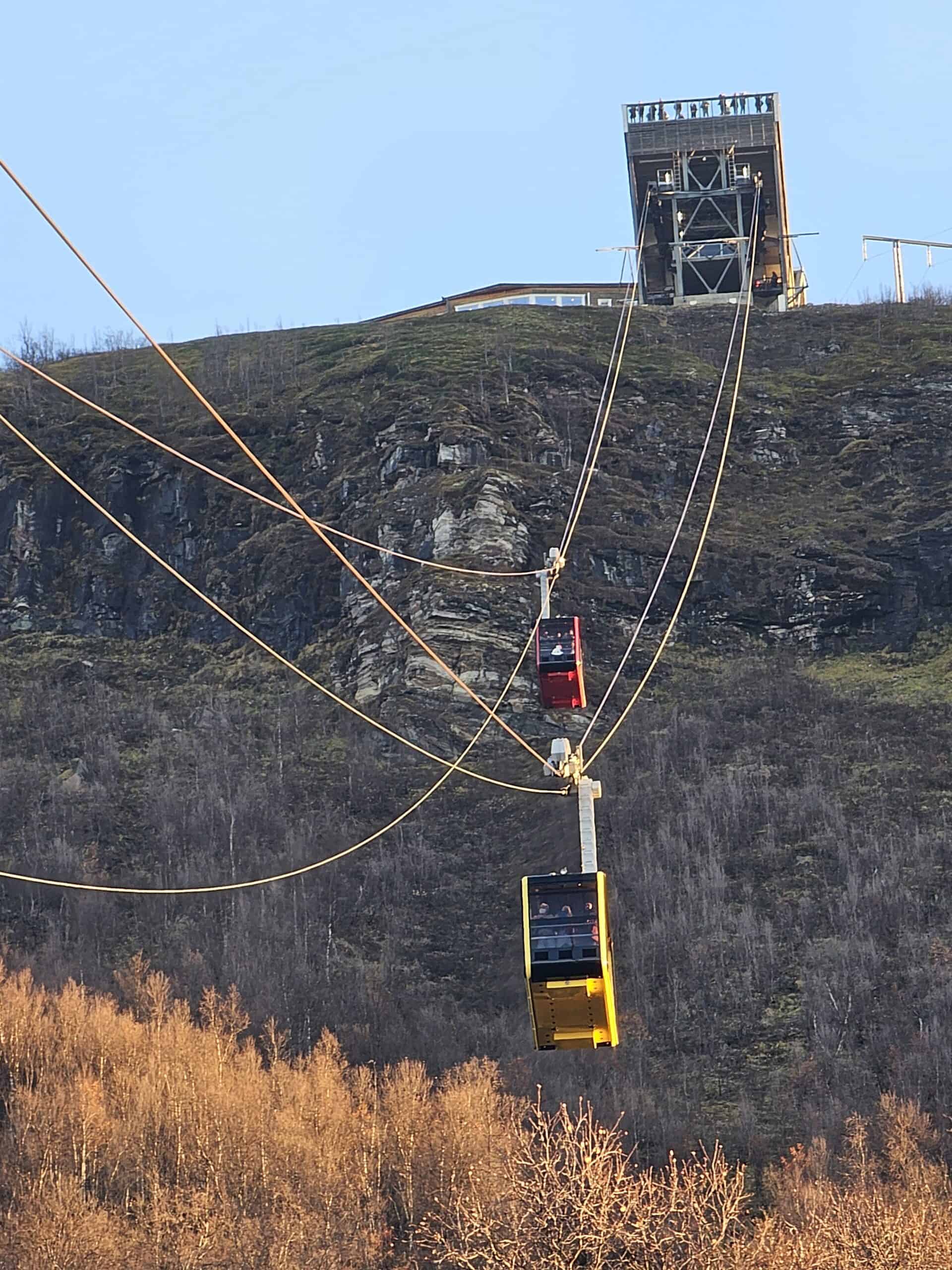 Cable cars ascending Mount Storsteinen in Tromsø during daylight.