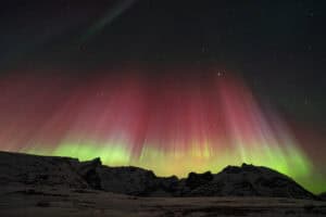 Spectacular aurora borealis display over snowy mountains in Tromsø, Norway.
