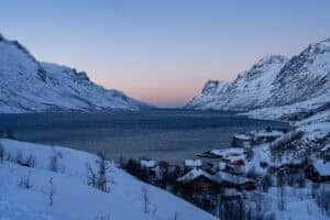 Beautiful snowy fjord landscape with mountains and village near Tromsø at dusk.