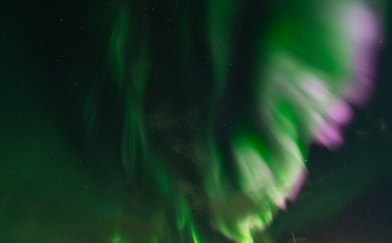 Spectacular aurora borealis display in Tromsø under a starry night sky.