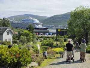 Tourists walking in a park with cruise ship and mountains in Tromsø.