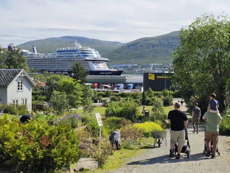 Tourists walking in a park with cruise ship and mountains in Tromsø.